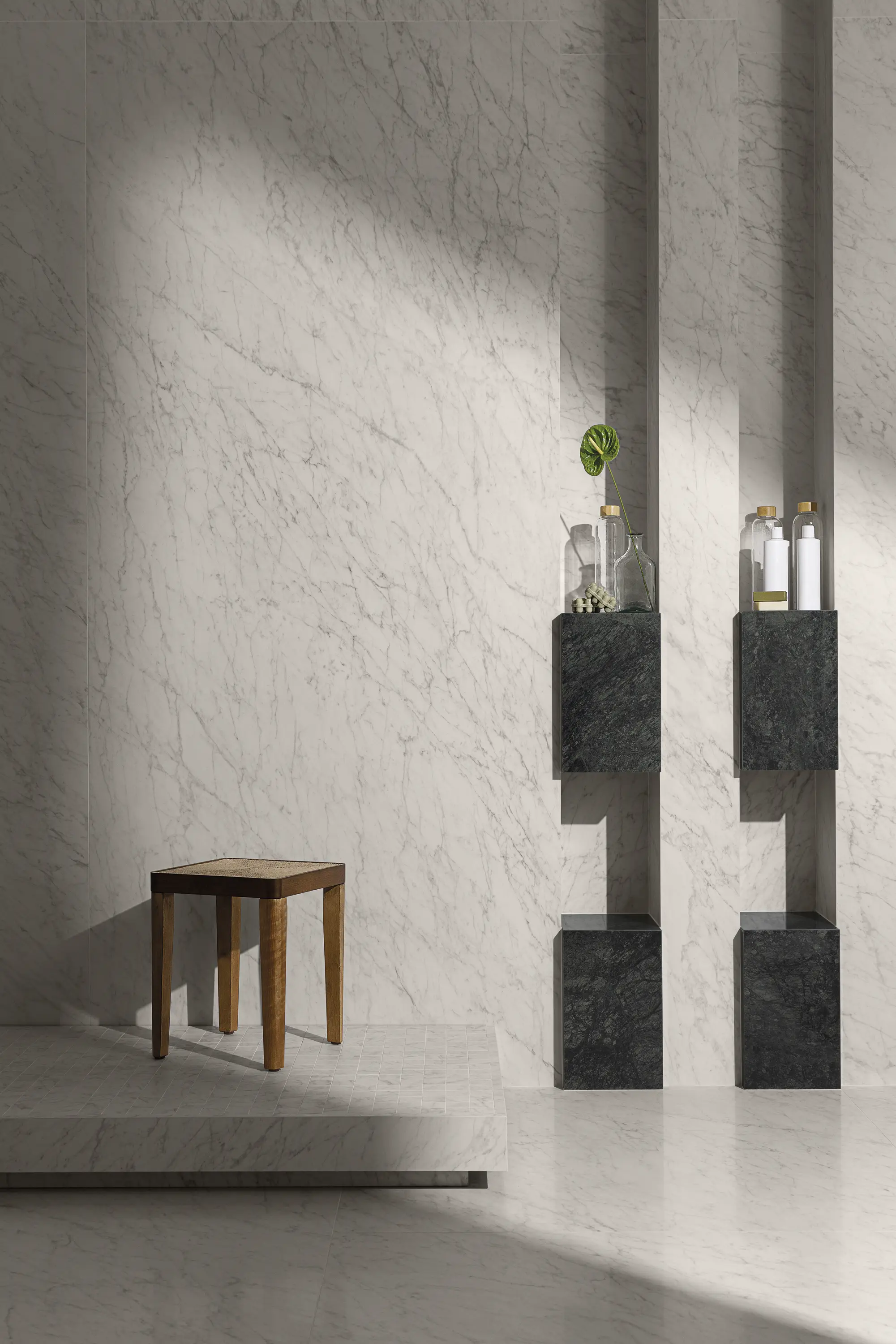 Textured light wall with small wooden stool and vertical display shelves with decor - Carrara Icon