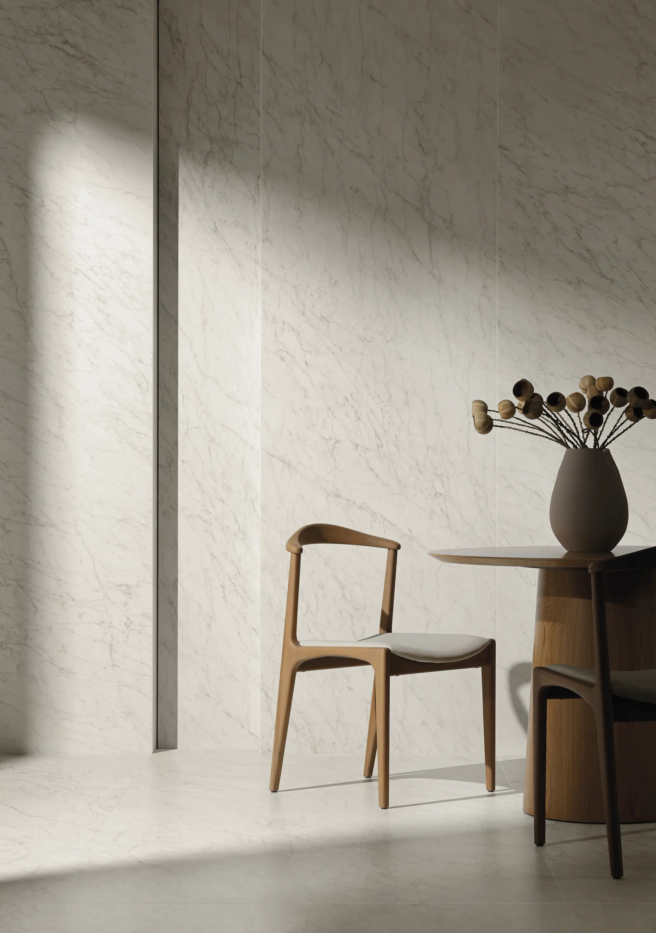 Neutral wall with soft texture, featuring a wooden chair and vase with dried branches - Carrara Icon