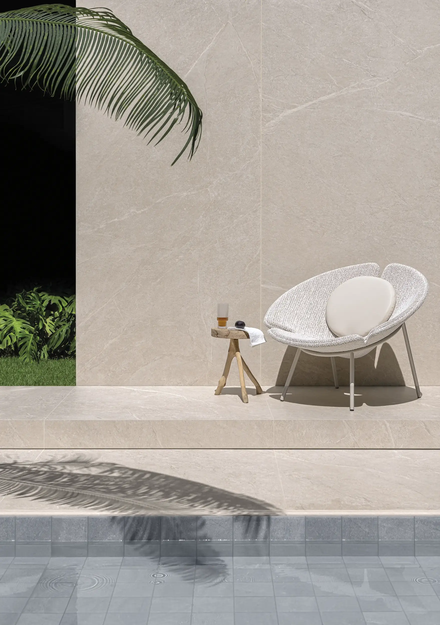 Outdoor lounge setting with beige wall tile, pool edge and modern white chair