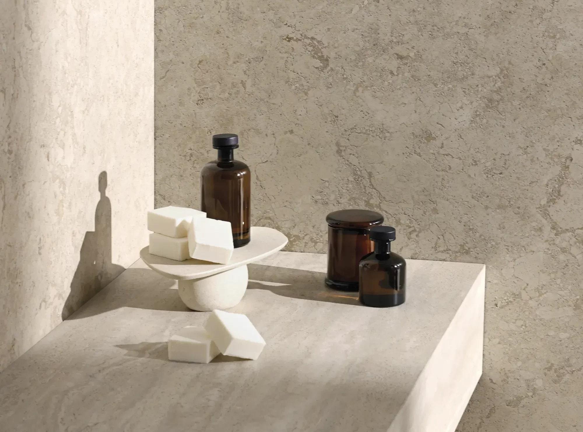 Beige stone-look countertop with minimalist objects and amber glass bottle - Aeterna X